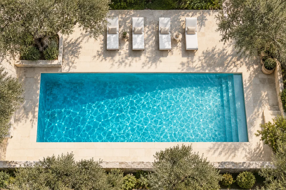 Vue plongeante sur une piscine rectangulaire bordée de transats blancs alignés