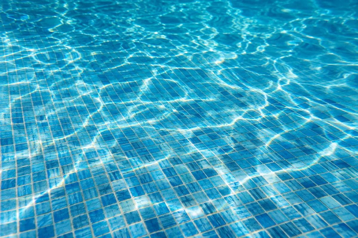 Fond de piscine en carrelage mosaïque bleu traversé de reflets de lumière